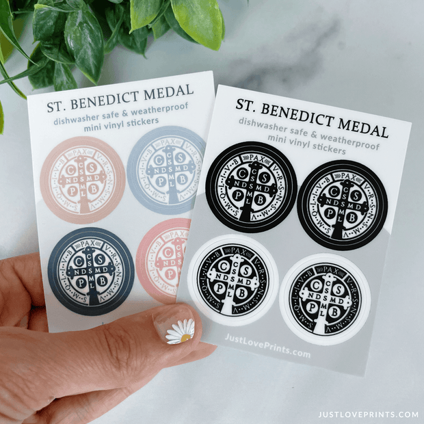 These sticker sheets contain 4 St Benedict medal stickers. One sheet has colored medals, with tan, blue, navy, and pink. The other sheet is black and white. They are dishwasher safe and weatherproof mini vinyl stickers. 