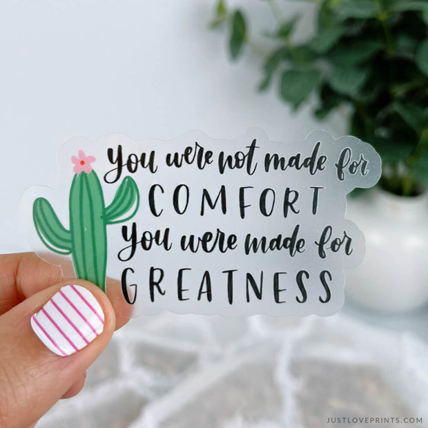 this sticker says, "you were not made for comfort, you were made for greatness." features a cactus on the side and is on clear vinyl. 