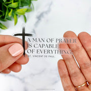 This sticker features St. Vincent de Paul’s quote, “A man of prayer is capable of everything,” alongside a simple black cross, giving it a minimalist yet impactful design.