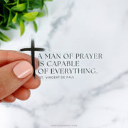 This sticker features St. Vincent de Paul’s quote, “A man of prayer is capable of everything,” alongside a simple black cross, giving it a minimalist yet impactful design.