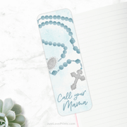 Bookmark featuring a blue rosary design with the phrase "Call your Mama" in elegant script, encouraging devotion to Mary. A gentle reminder of faith and prayer.