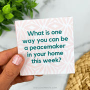 Hand holding a card with a peace-making question against a neutral background