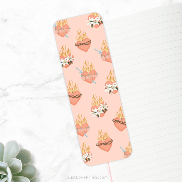 Bookmark featuring a repeating design of the Sacred Heart and Immaculate Heart, with flames, lilies, and swords on a soft pink background. A beautiful symbol of faith and devotion.