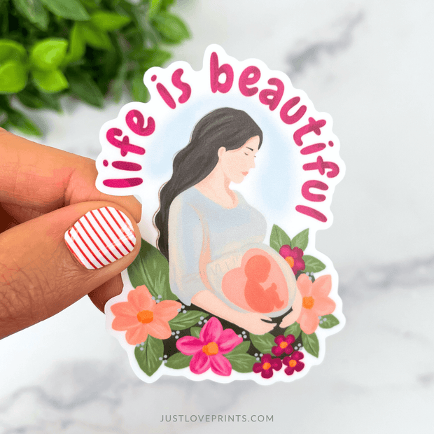 Sticker with illustration of a pregnant mother surrounded by flowers and the phrase “Life is Beautiful.”