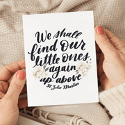 A decorative card featuring a handwritten quote, "we shall find our little ones again up above. -st. zelie martin," adorned with floral graphics