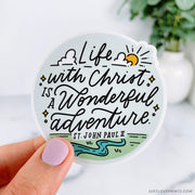 life with Christ is a wonderful adventure quote with river, green grass, and sun