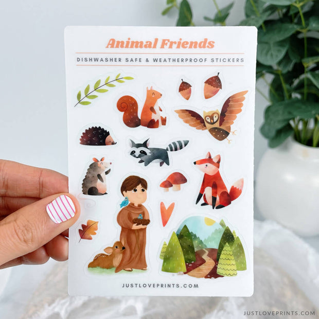 A sticker sheet of St. Francis's Animal Friends. There are stickers of a porcupine, raccoon, fox, owl, squirrel, acorns, a mountain scape, and St. Francis