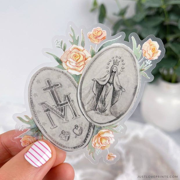 this silver miraculous medal sticker shows both sides of a miraculous medal with roses in the background. the medal is in silver.